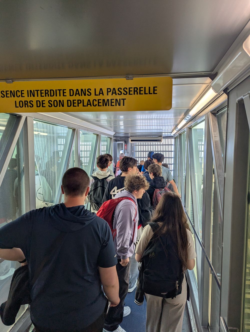 Le groupe avance dans la passerelle d'embarquement de l'aéroport.