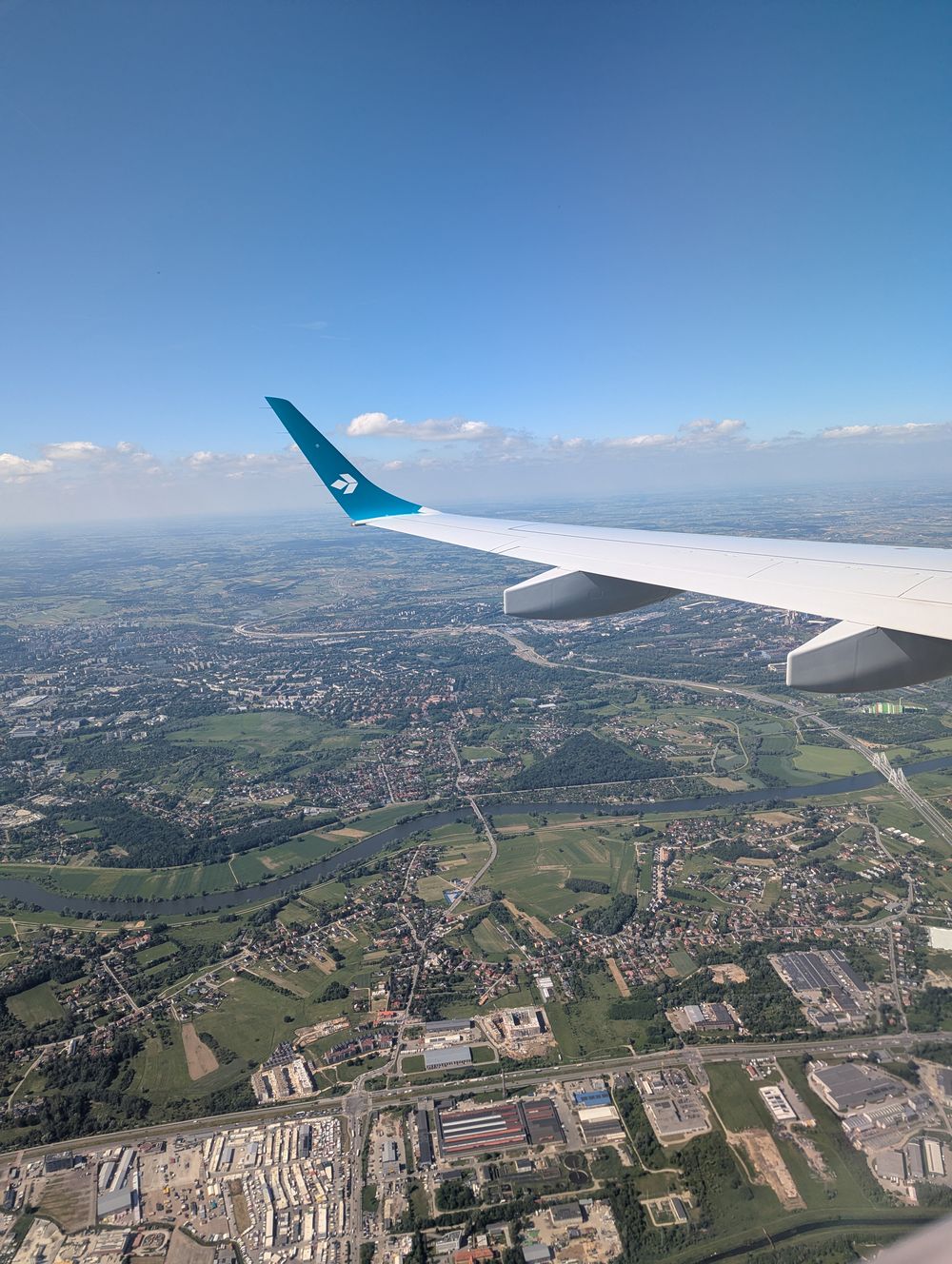 Vue aérienne d'une ville et d'une rivière, prise du hublot, avec l'aile de l'avion.