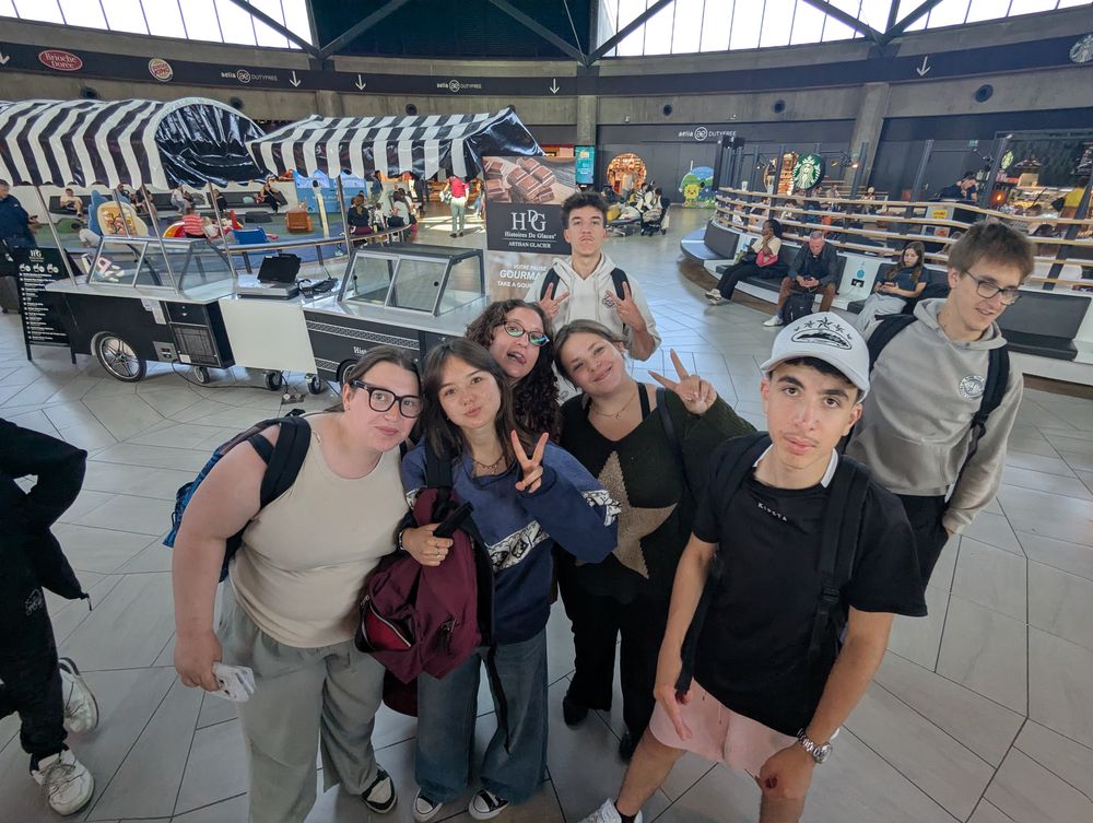 Un groupe d'élèves pose ensemble dans le hall du terminal avant le départ.