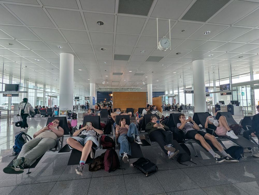 Des élèves se reposent, allongés sur les sièges de la salle d'embarquement.