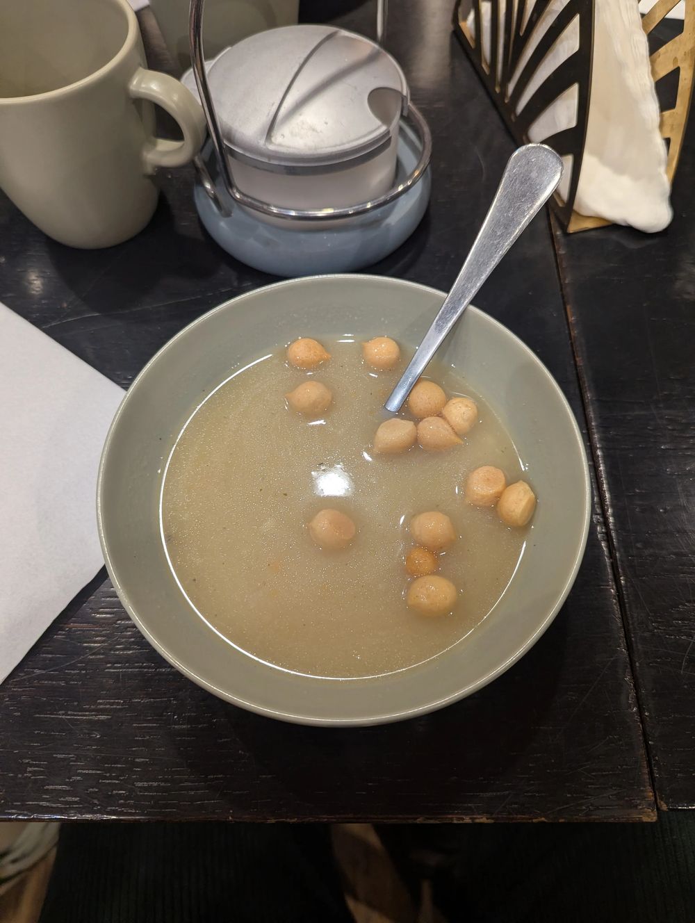 Une assiette creuse de soupe claire avec de petits croûtons.