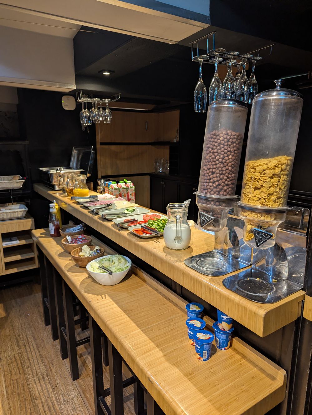 Buffet de petit déjeuner : distributeurs de céréales, charcuterie, légumes et yaourts.