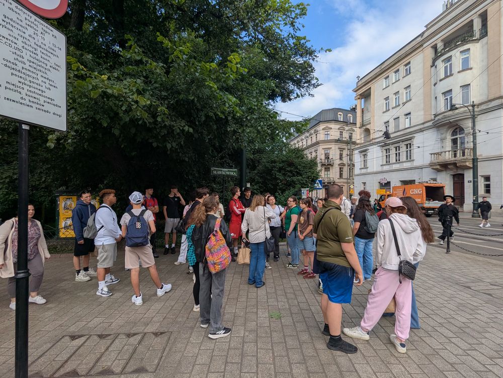Le groupe rassemblé près d'un panneau de la rue Sławkowska, immeubles anciens autour.