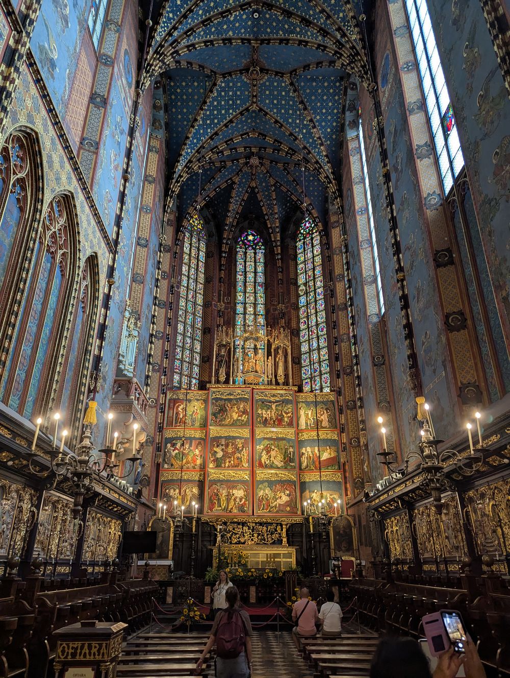 Intérieur gothique de la basilique : haute voûte bleue étoilée, vitraux et grand retable doré.