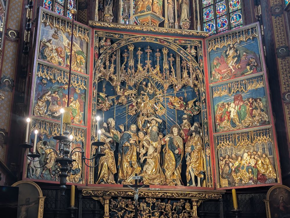Gros plan du retable sculpté et doré, avec de nombreuses figures en bois peintes.