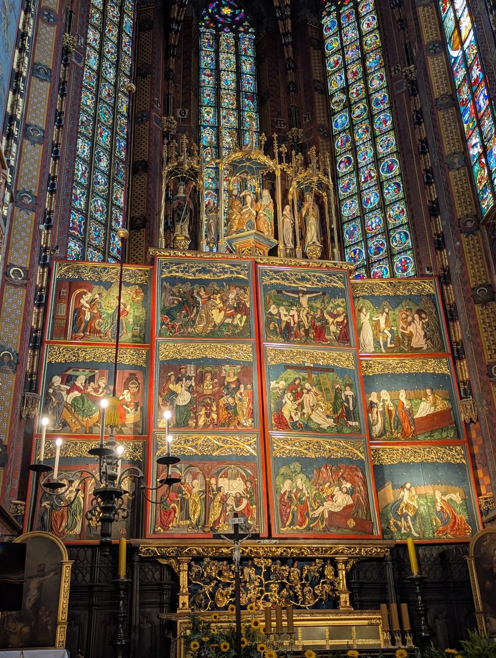 Le retable doré surmonté de hauts vitraux colorés.