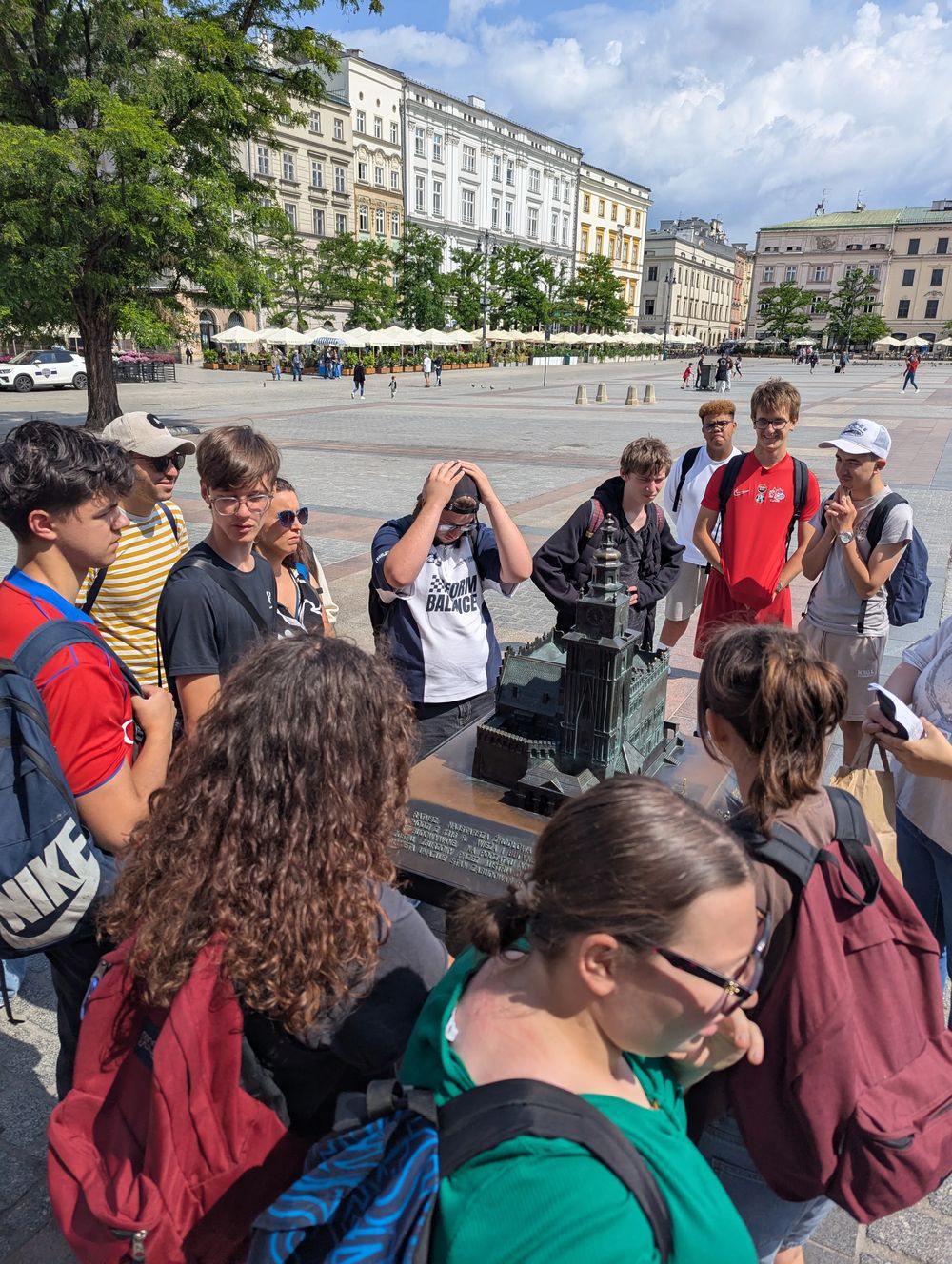 Le groupe et la guide rassemblés autour d'une maquette en bronze d'un bâtiment historique.