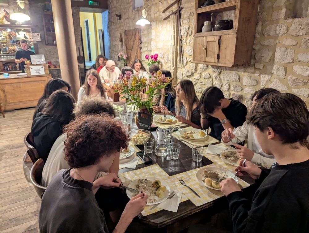 Longue tablée du groupe dans une salle voûtée en pierre, en plein dîner.