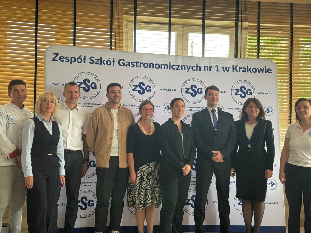 Photo des professeurs accompagnateurs avec le chef, la directrice et l'équipe de l'école hôtelière polonaise, devant la bannière « Zespół Szkół Gastronomicznych nr 1 w Krakowie ».