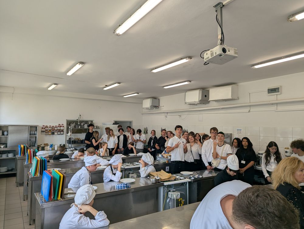 Grande cuisine de l'école : des élèves en tenue de cuisinier et toque, d'autres observent.