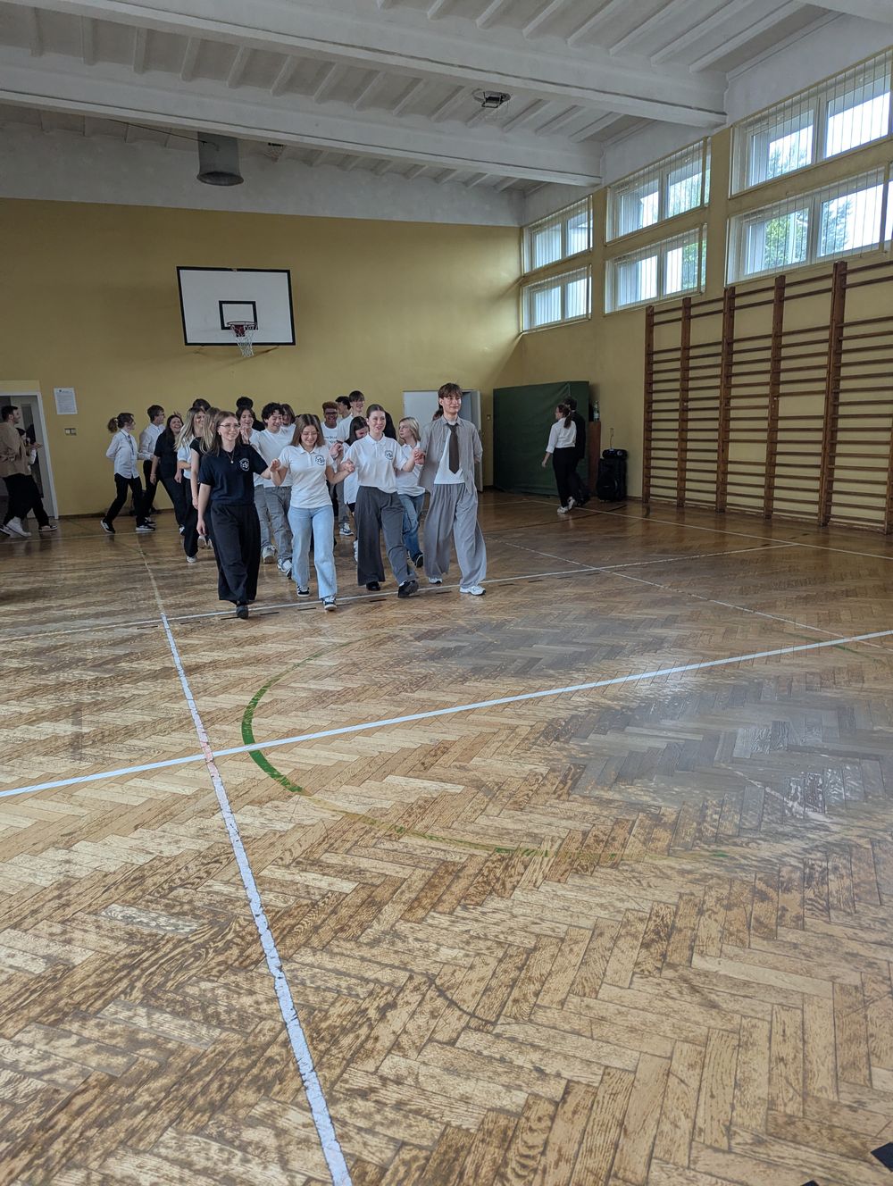 Le groupe avance par deux dans un gymnase en apprenant une danse traditionnelle polonaise.