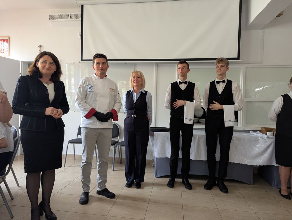 La directrice de l'école, le chef de cuisine et deux élèves en tenue de service posent ensemble.