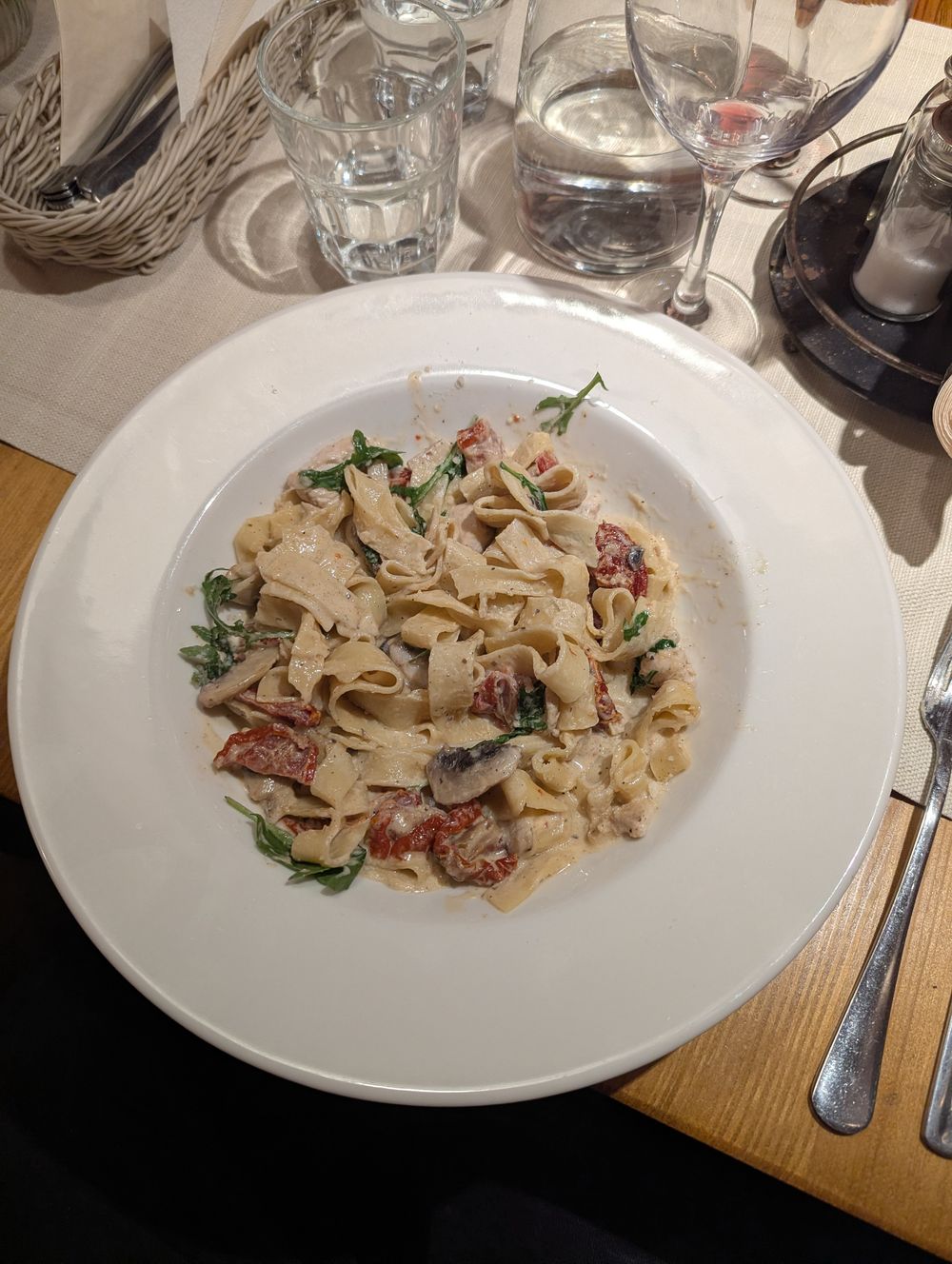 Assiette de tagliatelles au poulet en sauce crémeuse, avec champignons, tomates séchées et roquette.