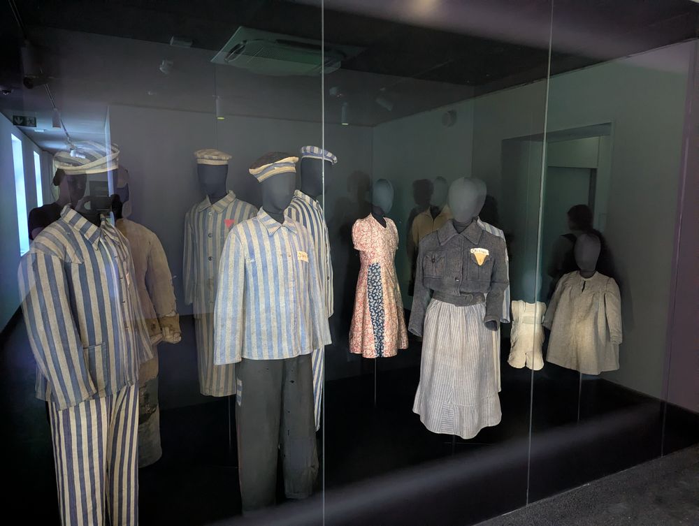 Vitrine présentant des tenues rayées de détenus ainsi que des vêtements civils.
