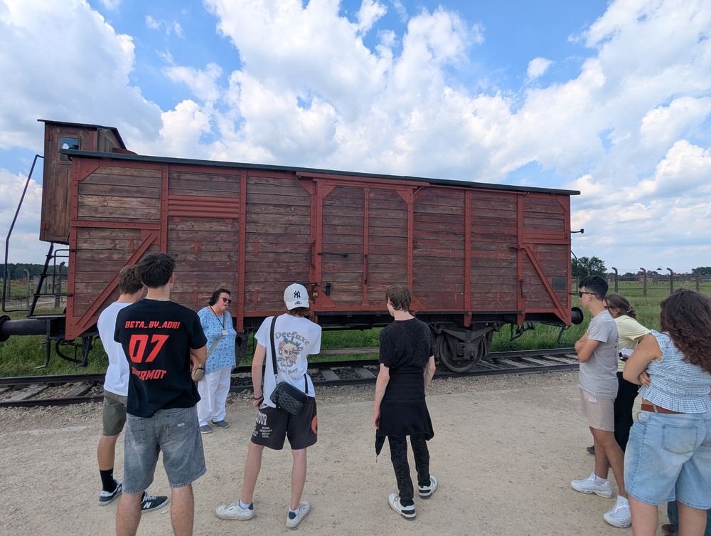 Le groupe et la guide devant un wagon de marchandises en bois, témoin des déportations, sur la rampe.
