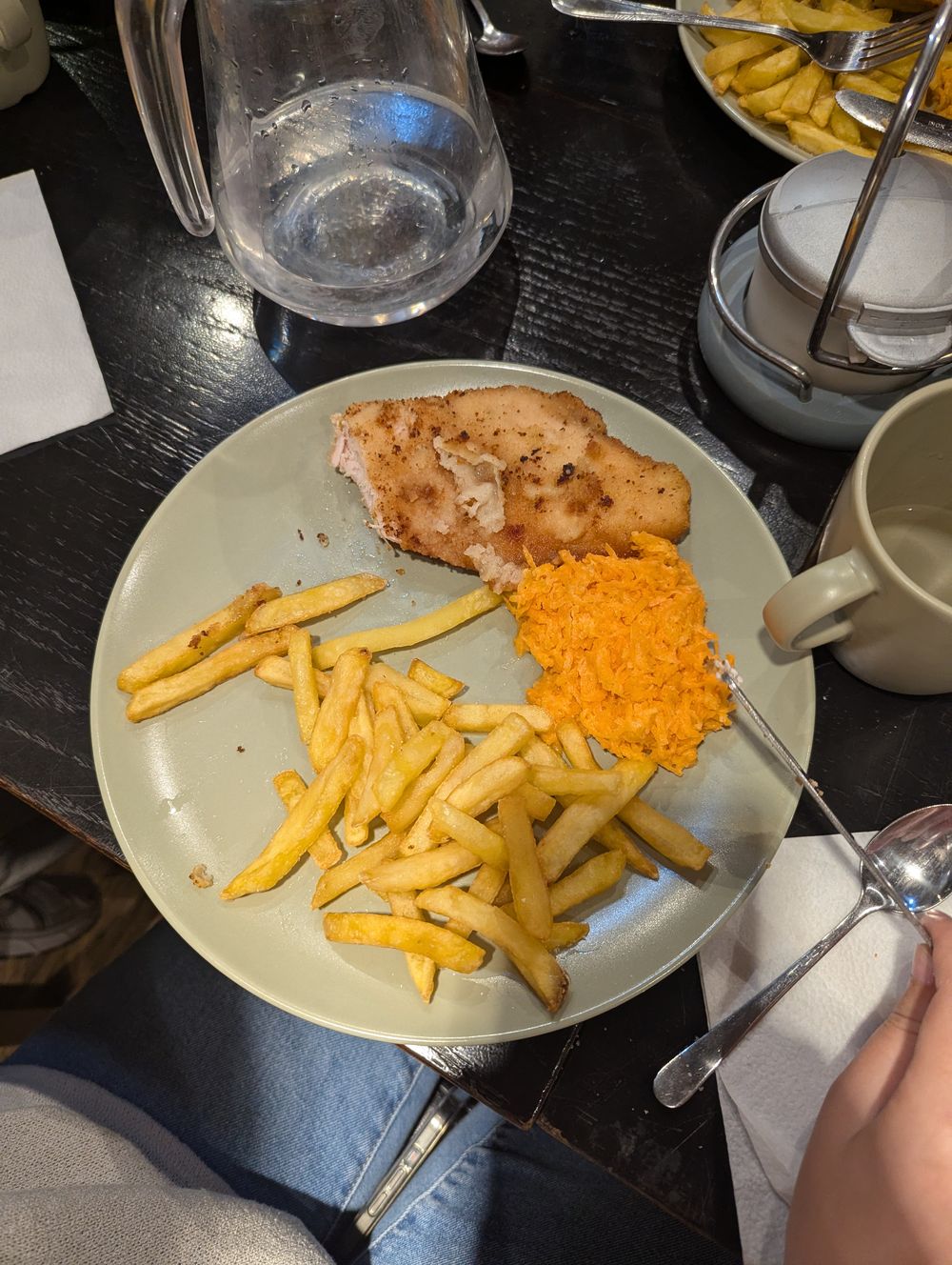 Une assiette d'escalope panée accompagnée de frites et de carottes râpées.