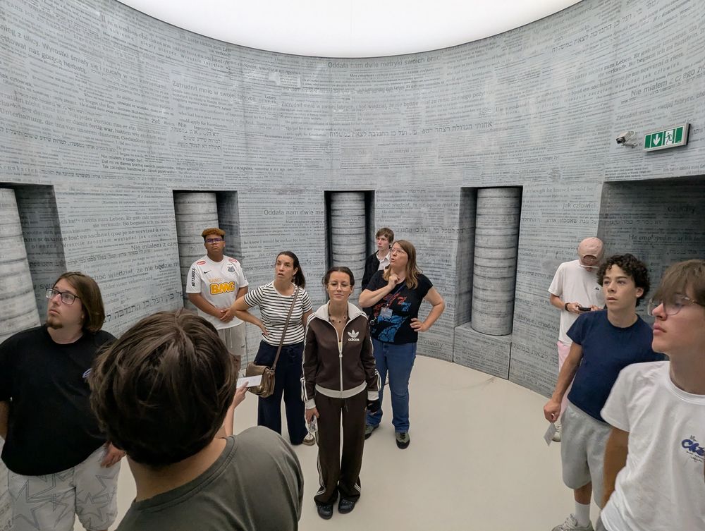 Une salle circulaire dont les murs sont couverts de témoignages de survivants, en plusieurs langues.