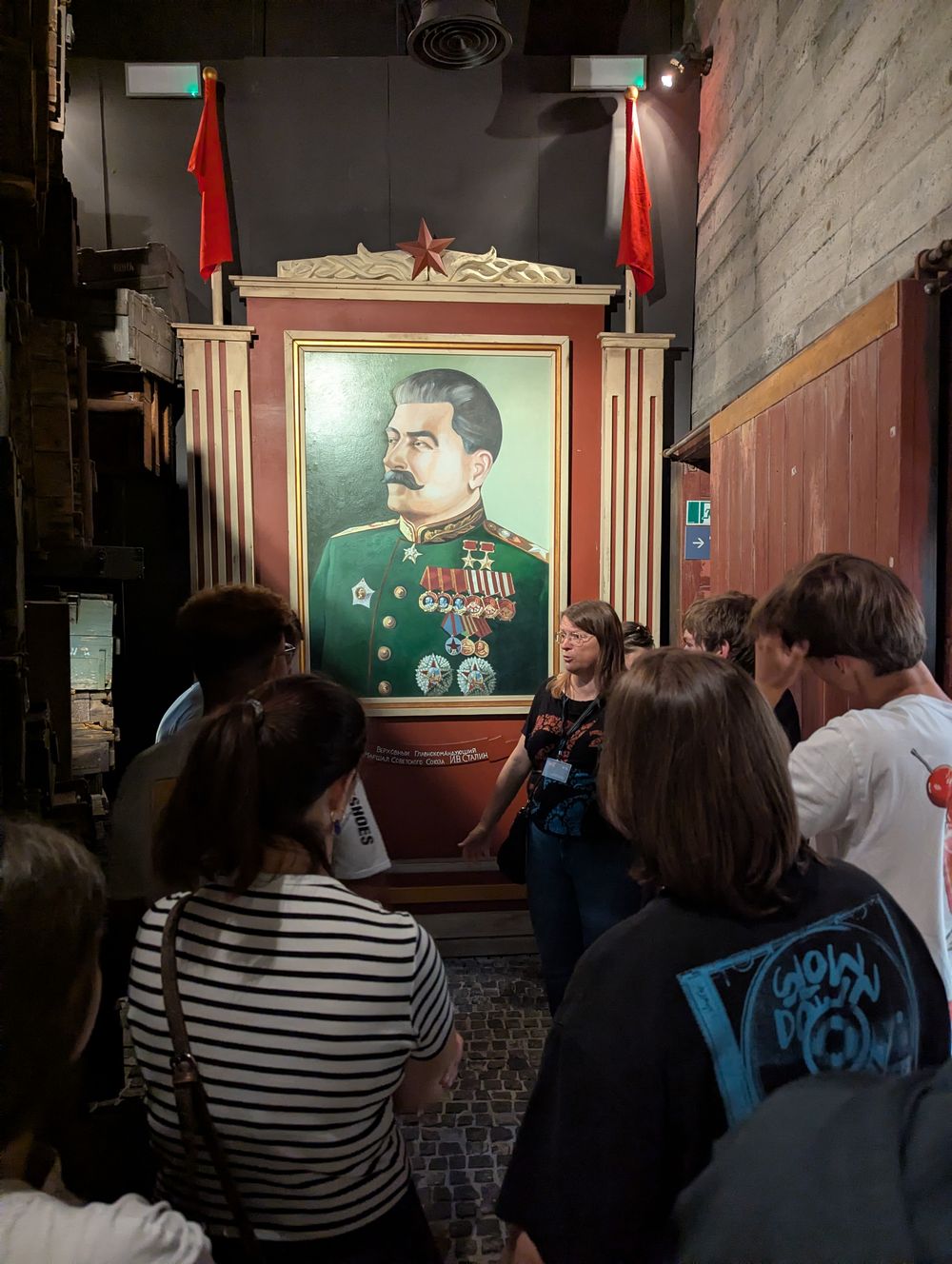 Devant un grand portrait de Staline encadré de drapeaux rouges, la guide évoque la période d'après-guerre sous influence soviétique.