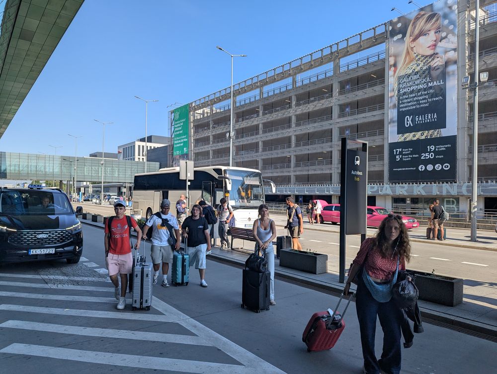 Le groupe arrive à l'aéroport de Cracovie avec les valises, près de l'arrêt des bus.
